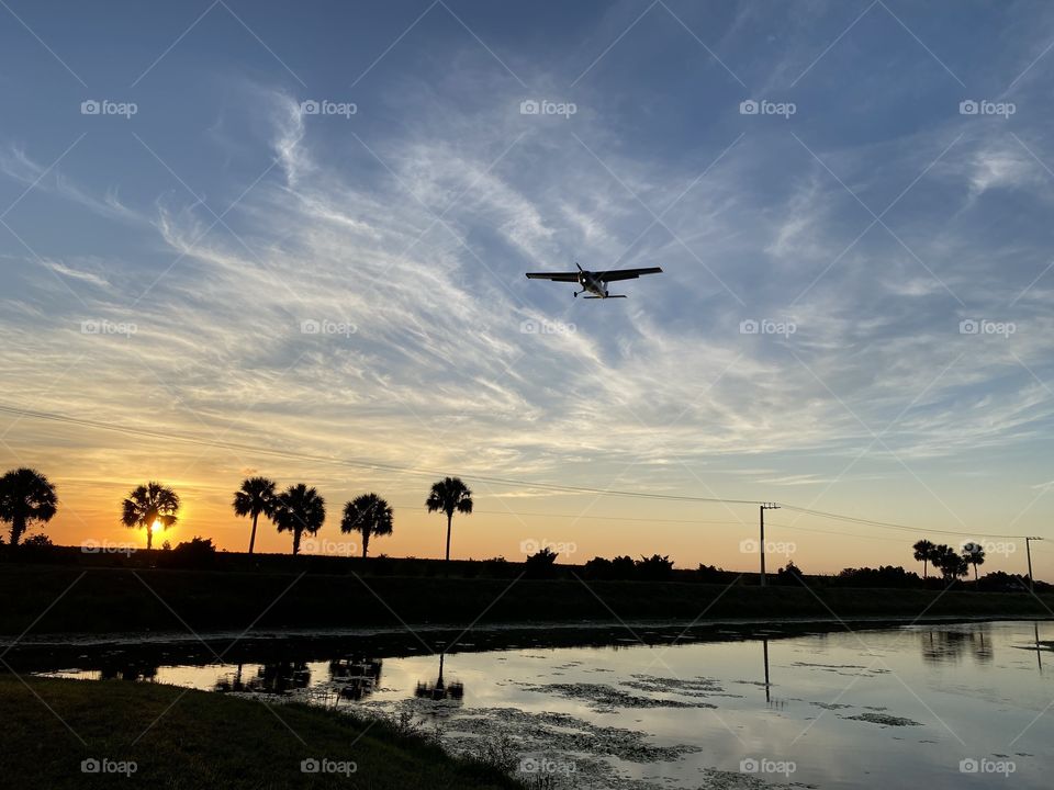 A small plane prepares to land as the gorgeous sun sets below. 