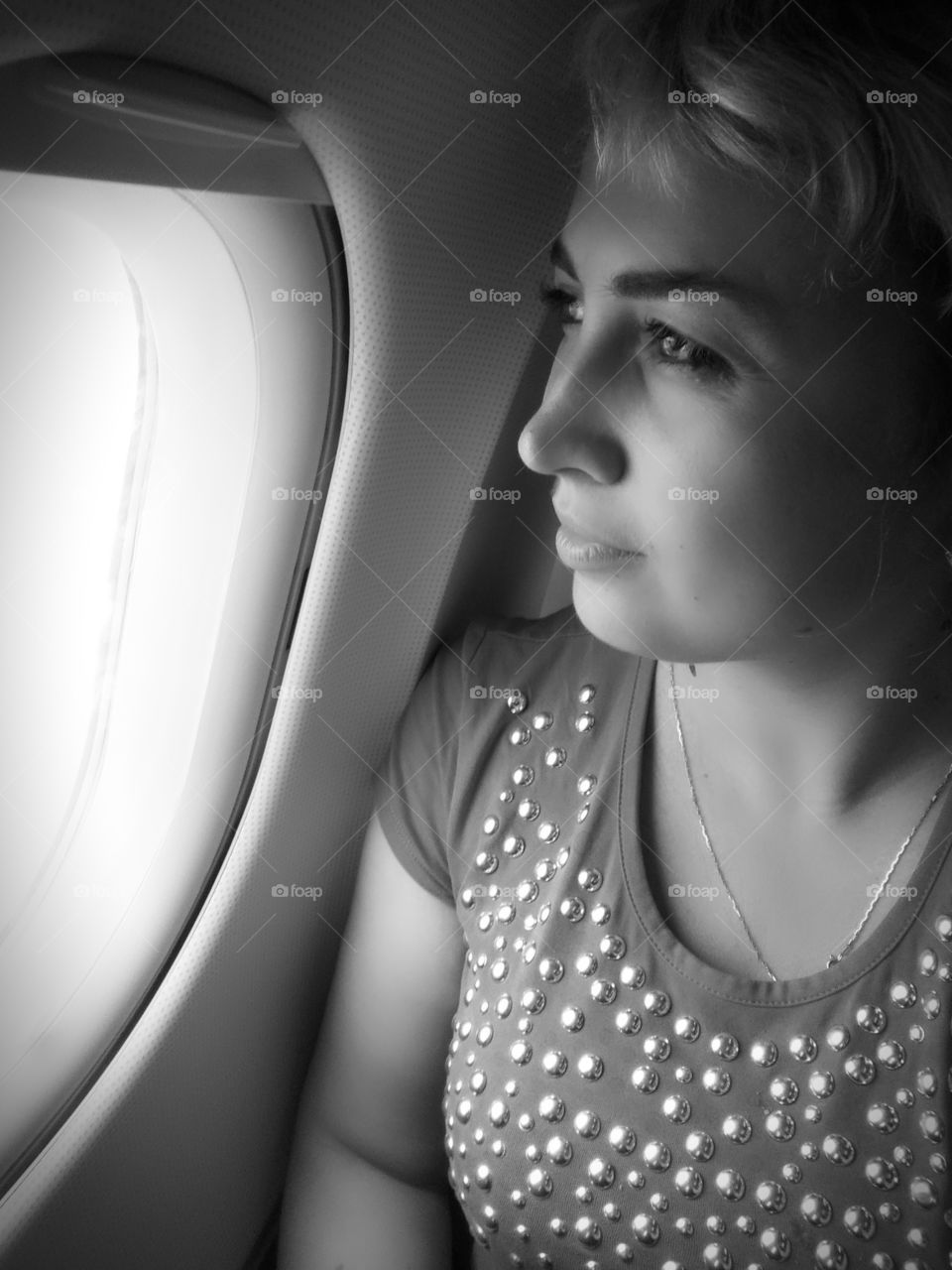 женщина смотрит в иллюминатор самолёта при взлете