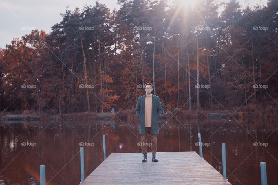 A man in a raincoat on the background of a lake