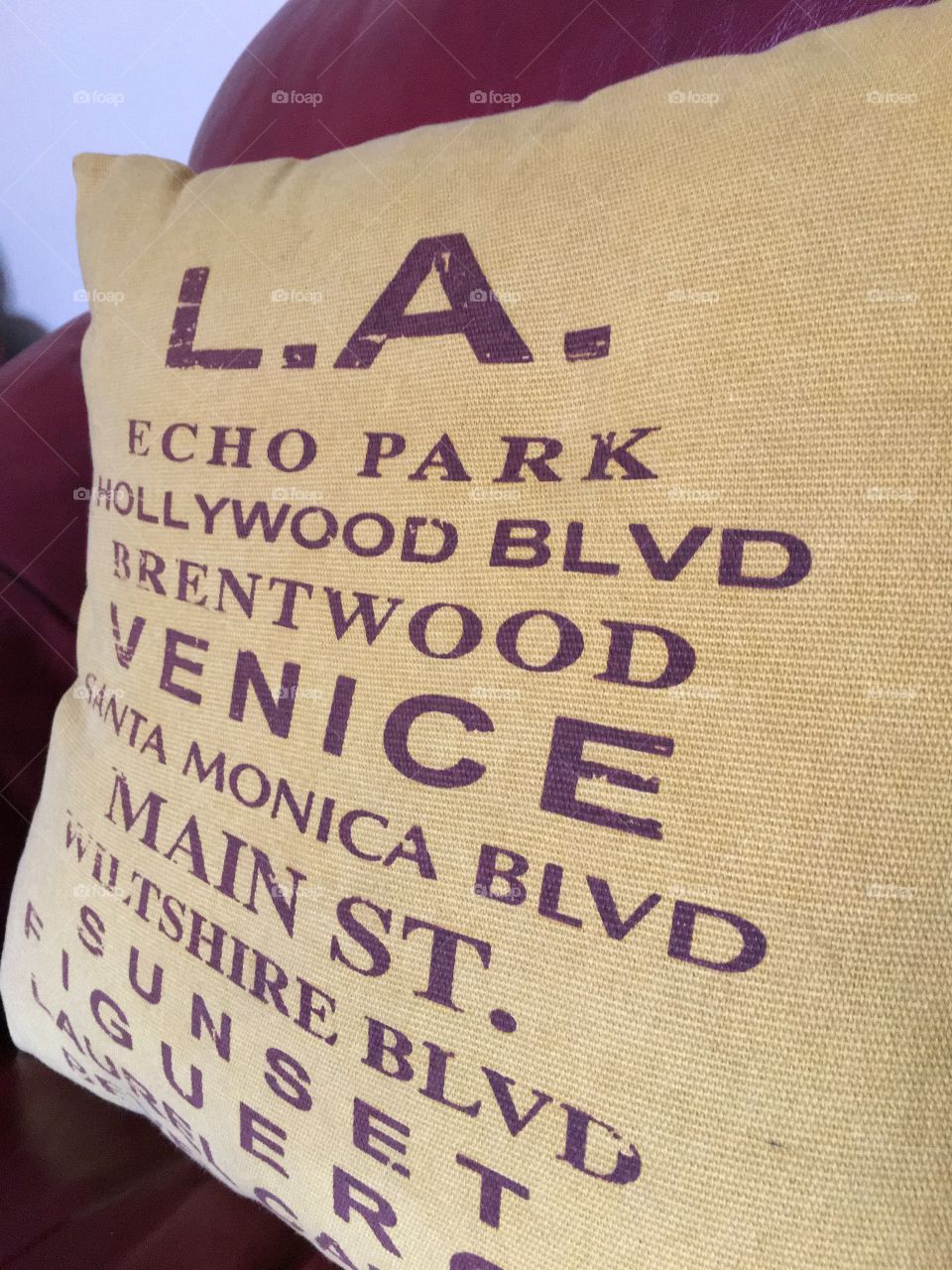 Yellow Pillow on beefing leather chair with names of California places Hollywood, LA, etc