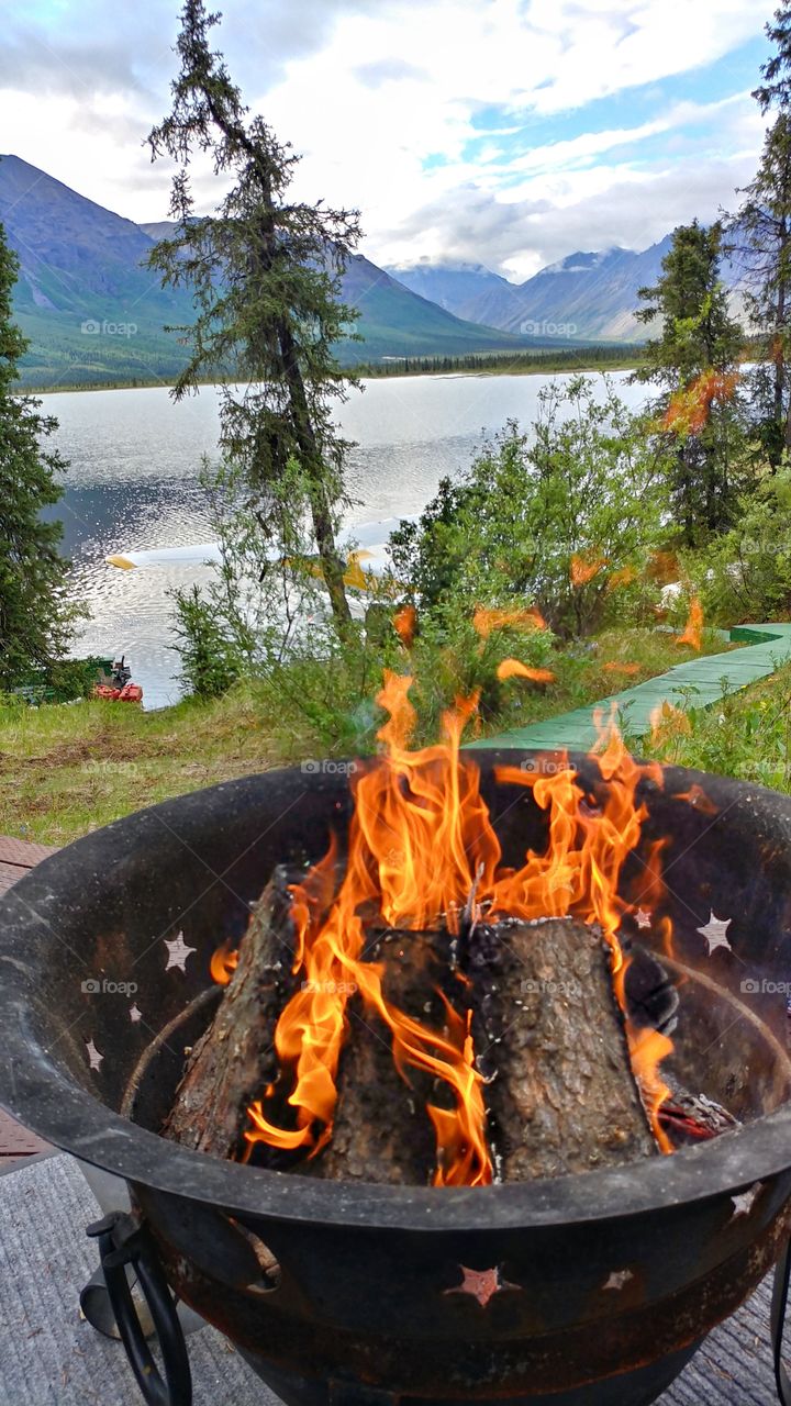 Mezmerizing flames of a fire pit compete with the beauty of Tanada Lake, Alaska