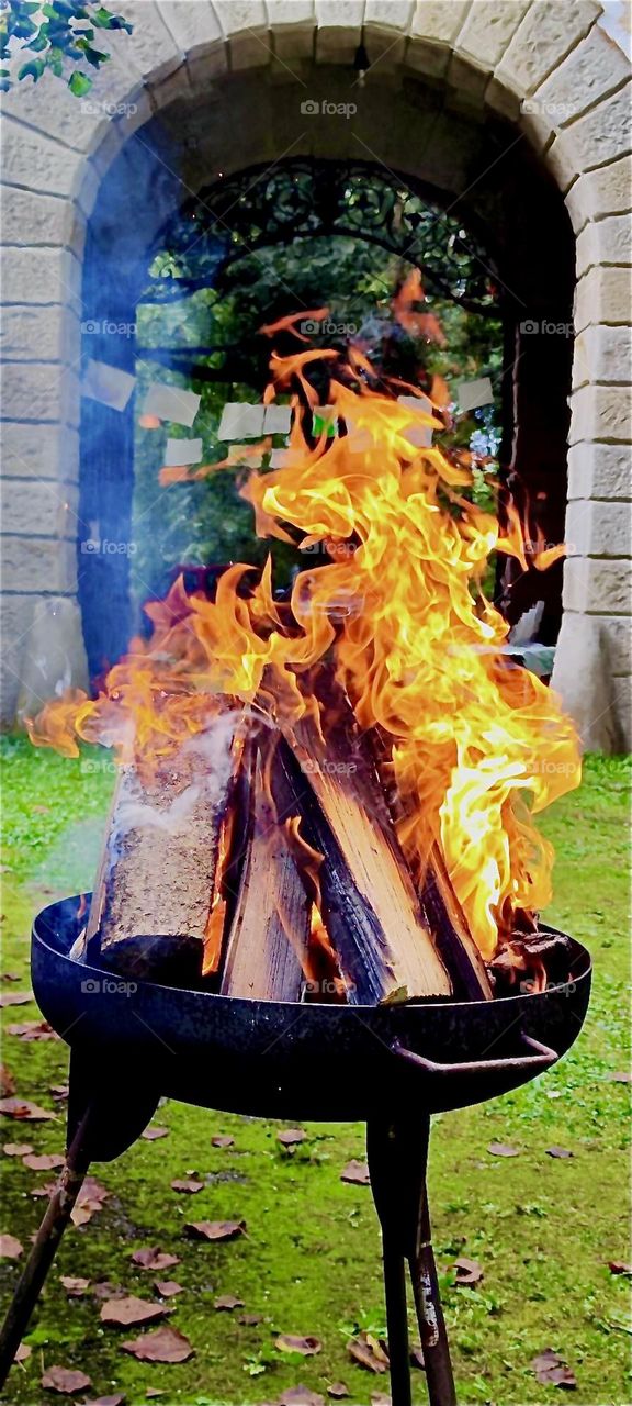 The bonfire is ablaze in the cast iron fire bowl filled with chunky fire logs in the garden of the old castle of “Steinach” in “Lower Bavaria”, Germany at the “Market of Possibilities”, an arts and crafts fair. 2024. Hypnotic Productions