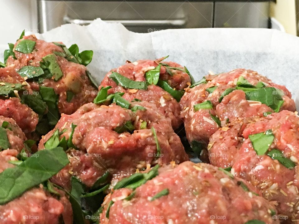 Food prepping Italian meatballs filled with spinach before cooking
