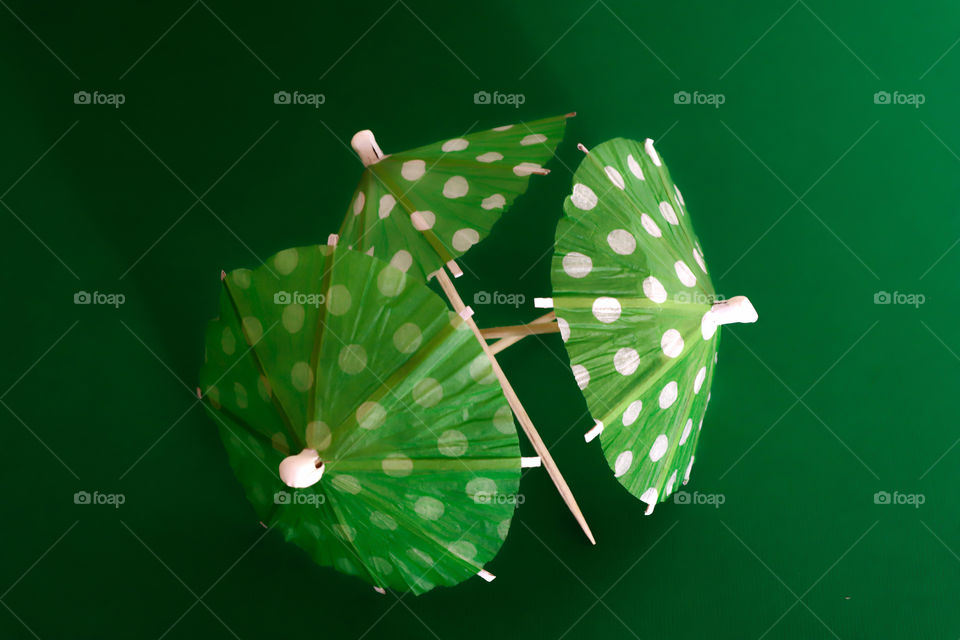 Green umbrellas with white dots on green background