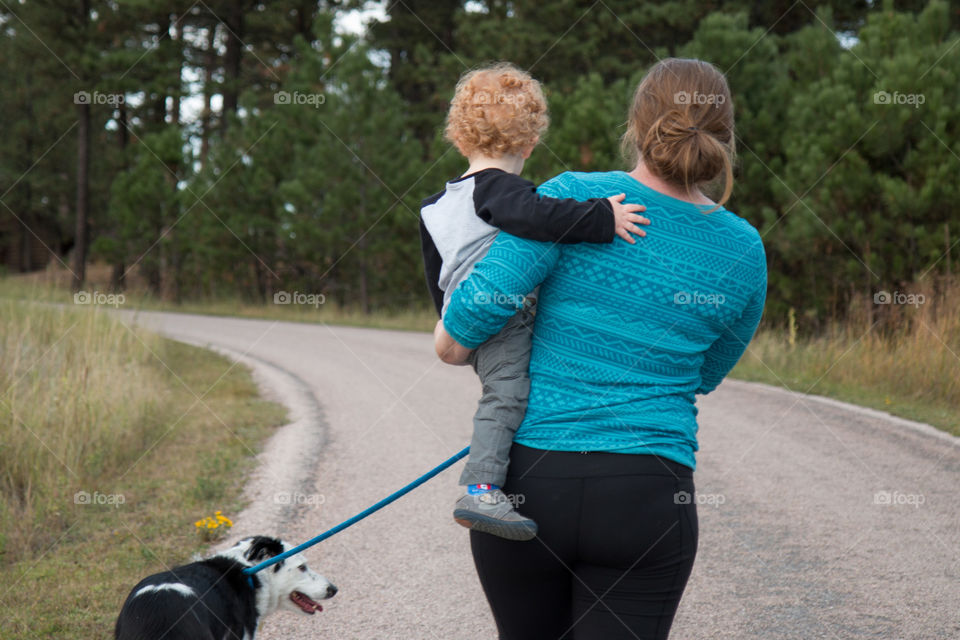 A pregnant mom carries her toddler and walks the dog