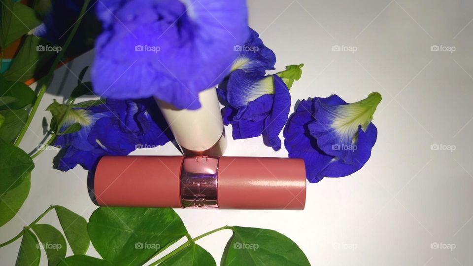 lipstick against a blue flowers and green leaves background