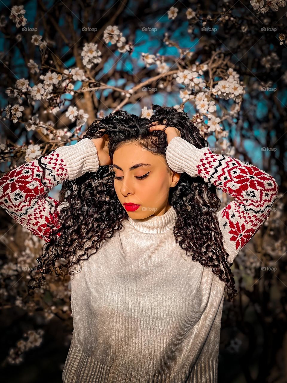 Curly-haired girl and blossoms in the spring air