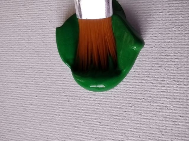 Unfiltered, beautiful, lovely close-up of green paint and a paint brush on a canvas