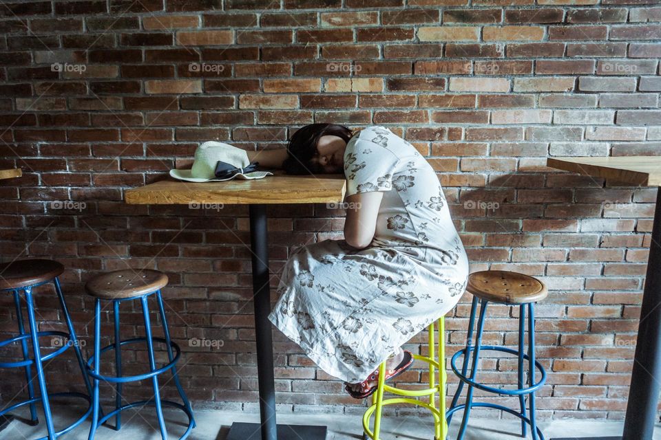 a woman who looks tired on a cafe table is pensive with a sad expression and thinking about something