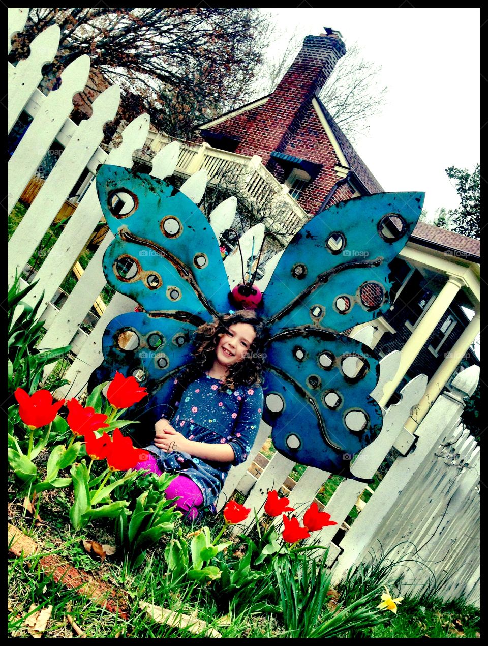 Smiling little girl with butterfly wings in garden