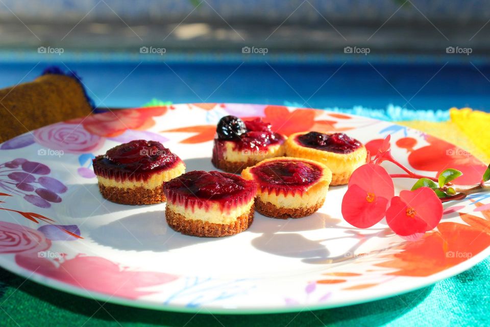 Small cheesecake with forest fruits on a flower plate