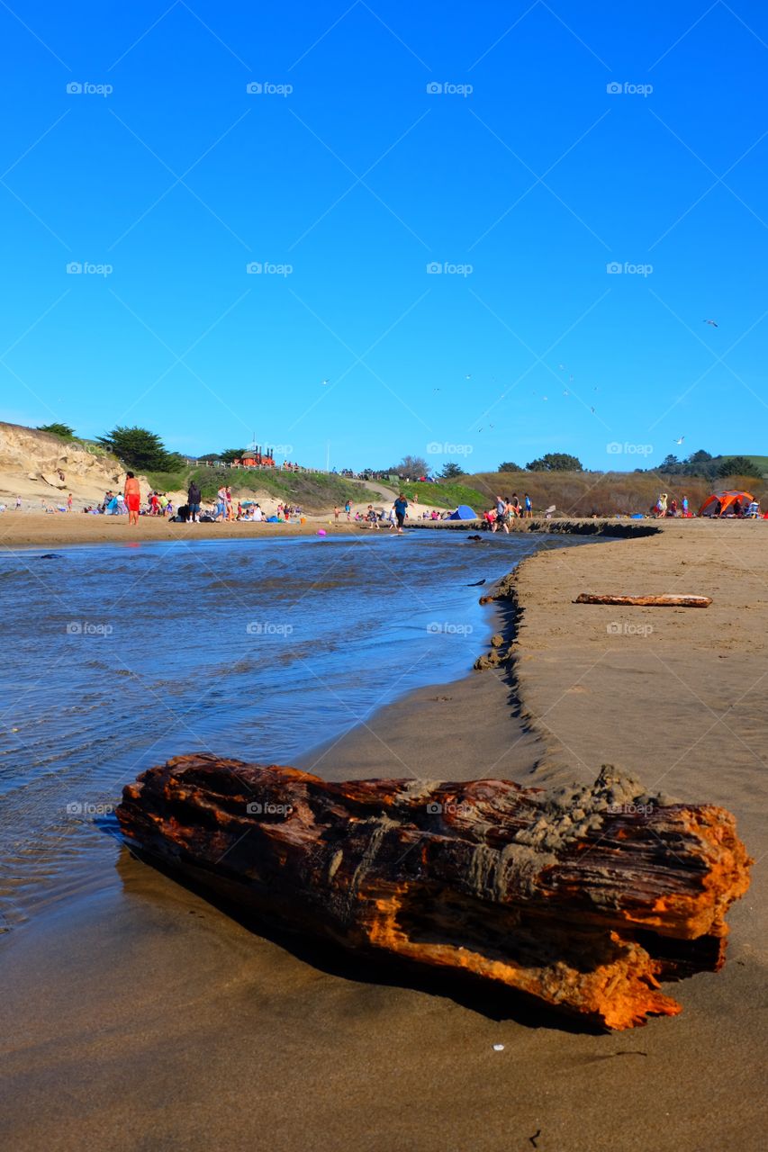 People enjoying beach, at the mouth of a river, picnic and tents