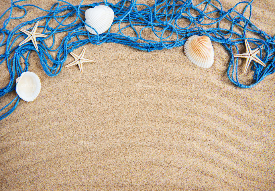 Fishing net with shells on a sand background