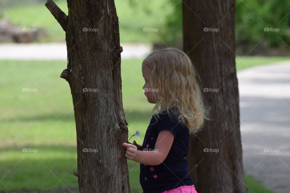 Girl by trees. Toddler enjoying nature 