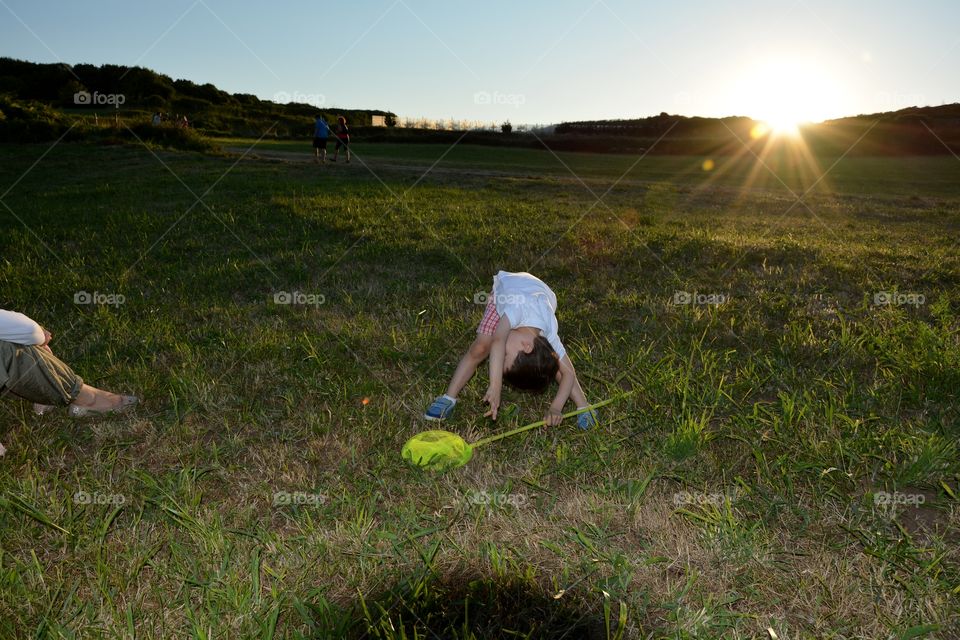 boy playing in the field during the sunset