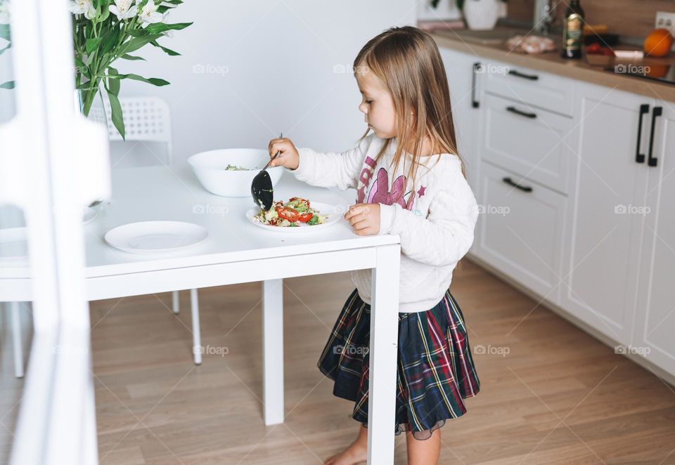 Little girl helping on kitchen at home 