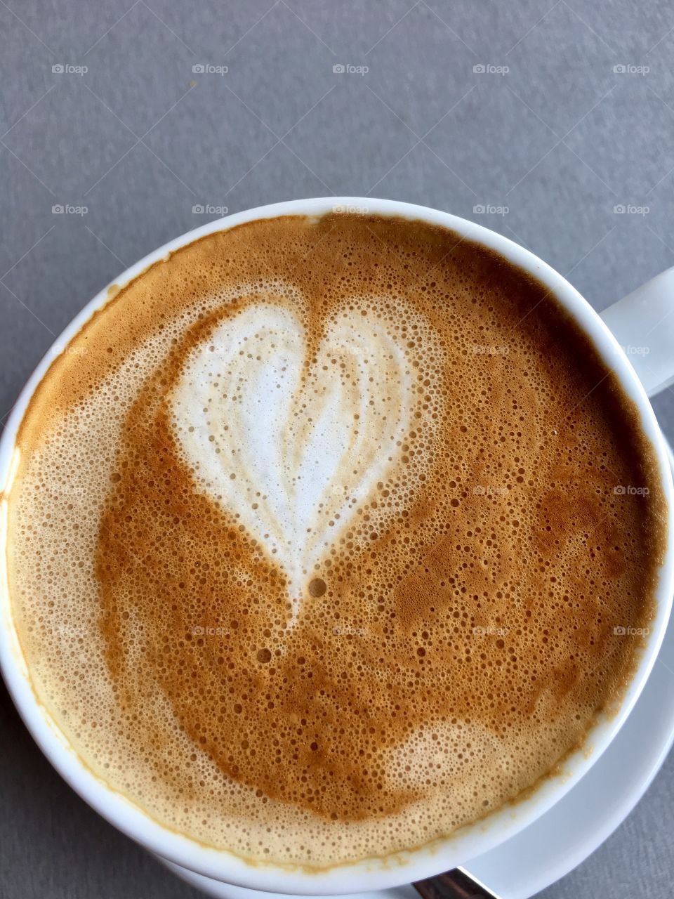 White coffee cup and saucer cafe latte heart shape in froth foam cream 