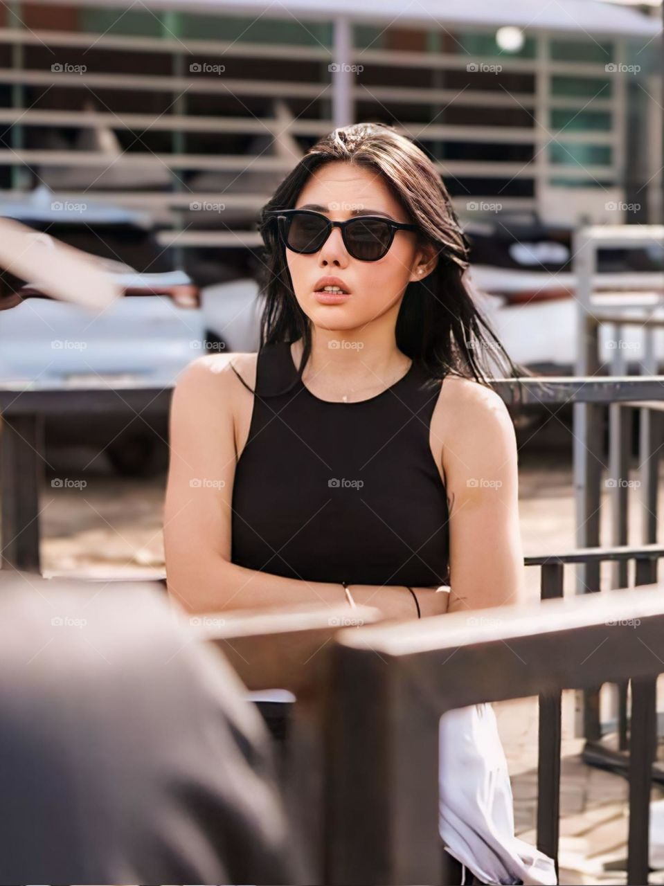 The young woman wearing sunglasses and a black bra stood and folded her arms