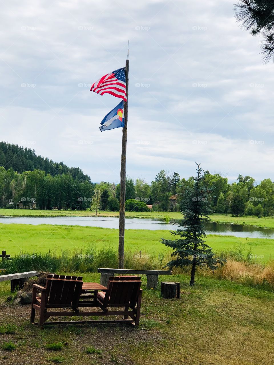 US and Colorado flags outdoors near lake