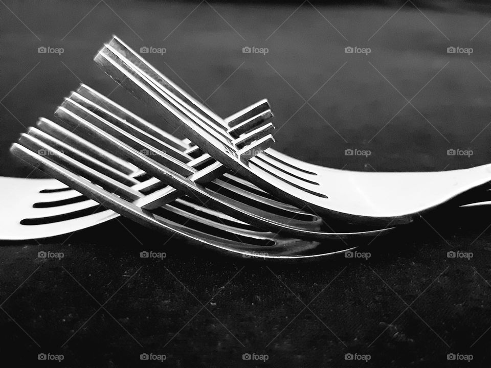 Close up four forks piled isolated on black background. Made from stainless steel