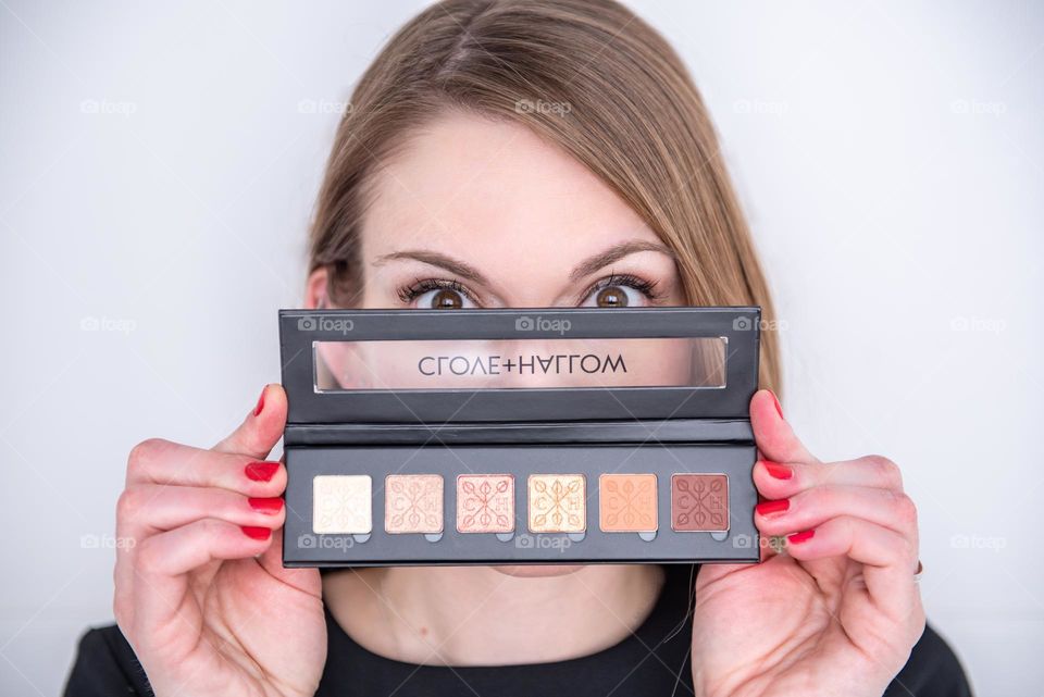 Woman holding a Clove + Hallow eye shadow palette over her face 