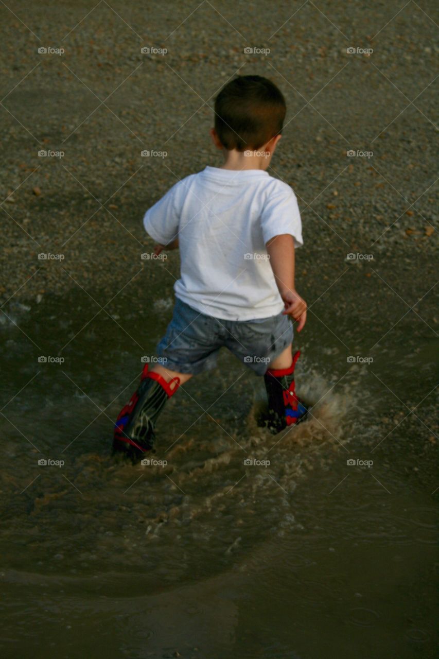 Splash. A toddler splashing in puddles in his rain boots. 