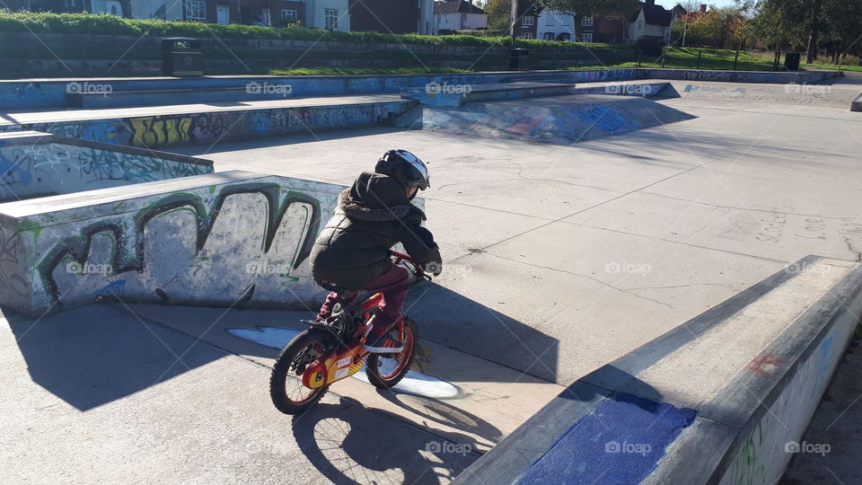 boy on bike speeding down skate park ramp