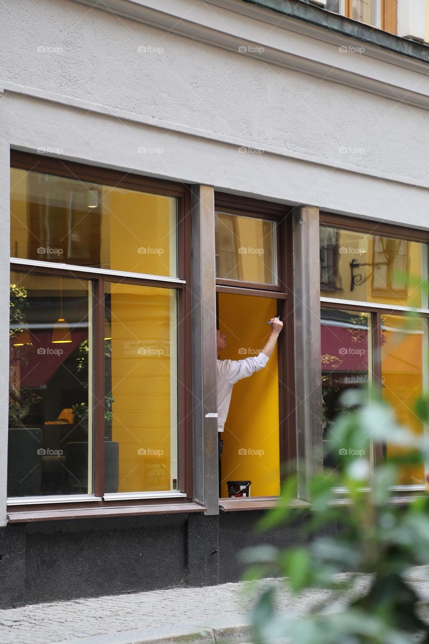 Yellow painted walls behind the windows and a person standing in an open window 