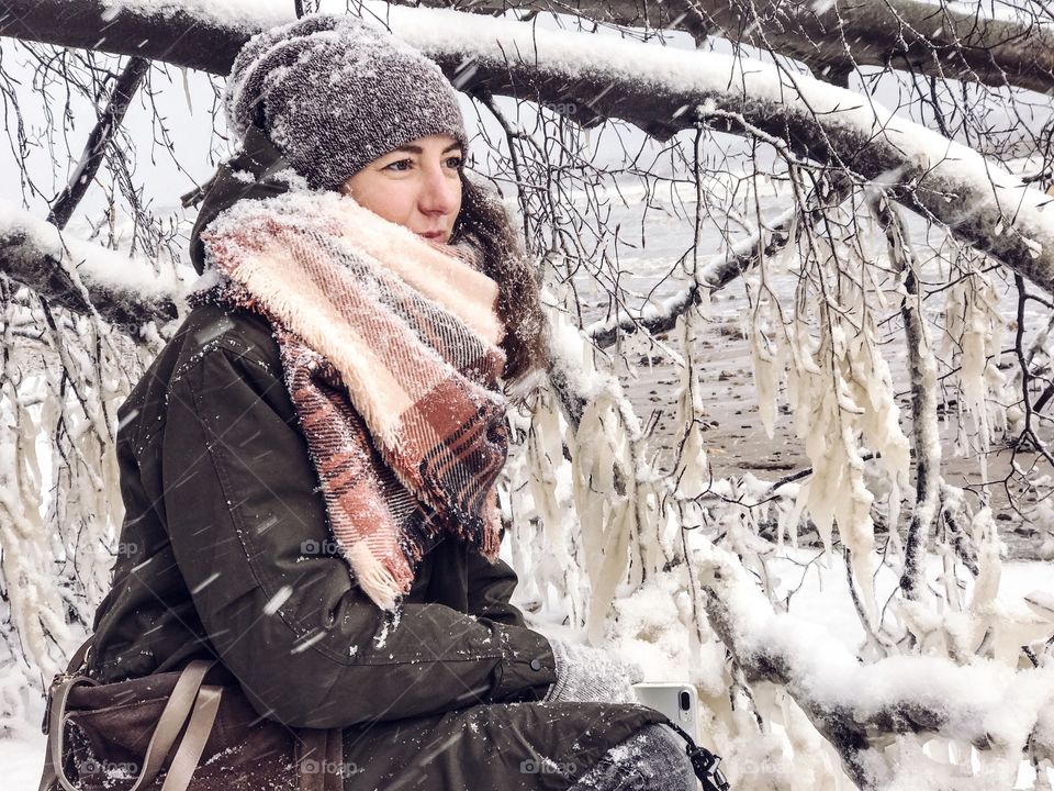 Woman in warm clothes near branches with snow