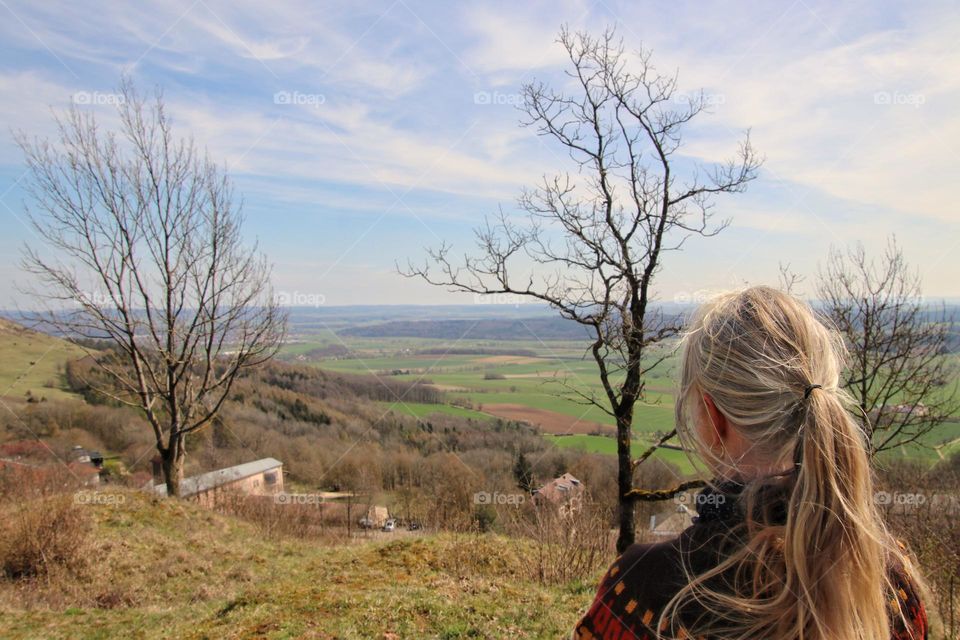 Rear view of woman with blonde ponytail looking at nature in spring