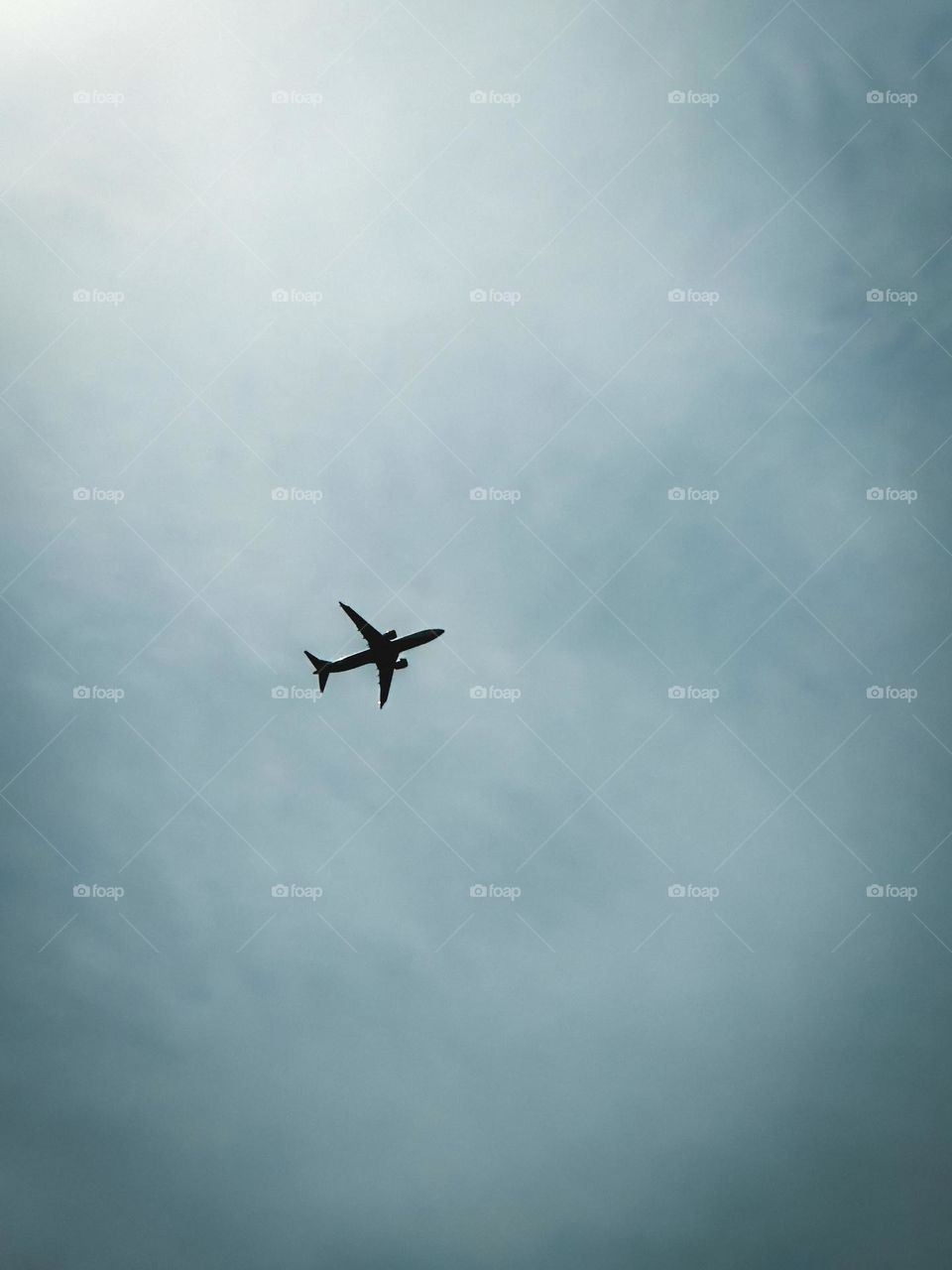 An airplane soars through the cloudy grey sky.