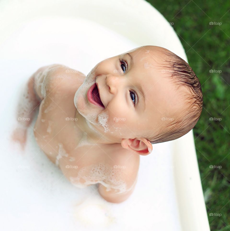 Smiling boy bathing in tub