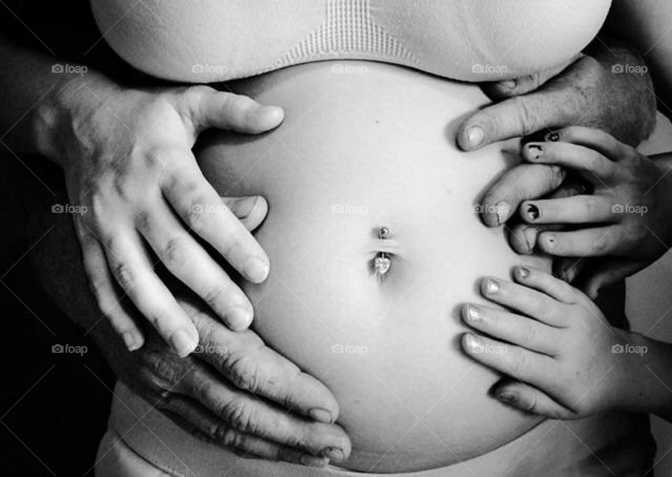 Mother, father & siblings hands touching mothers pregnant belly