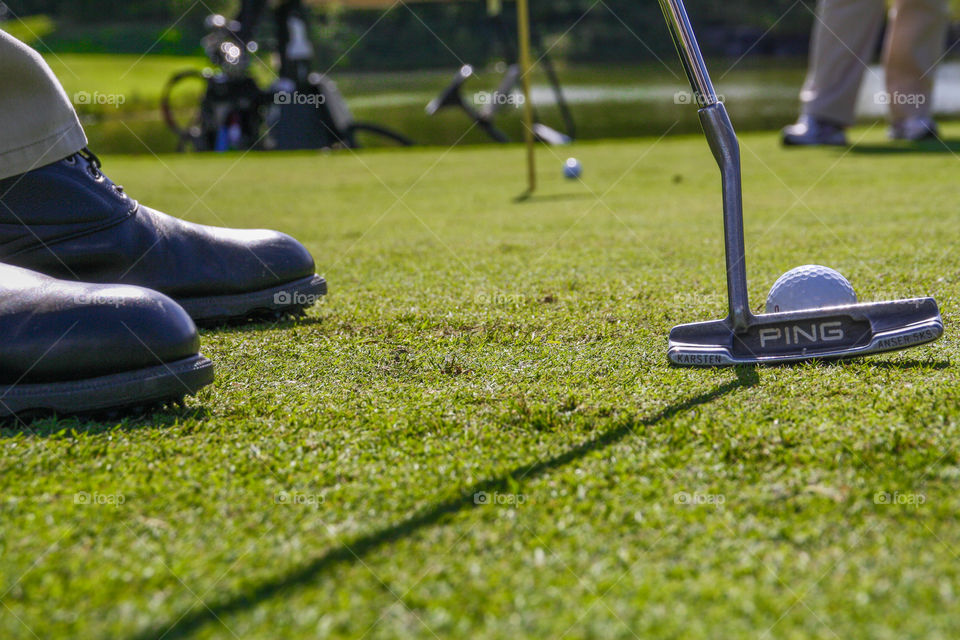 A golfer puts the ball towards the hole in the green