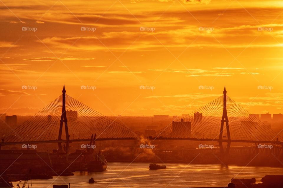 Golden twilight cover silhouette the Bhumibol landmark bridge in Bangkok