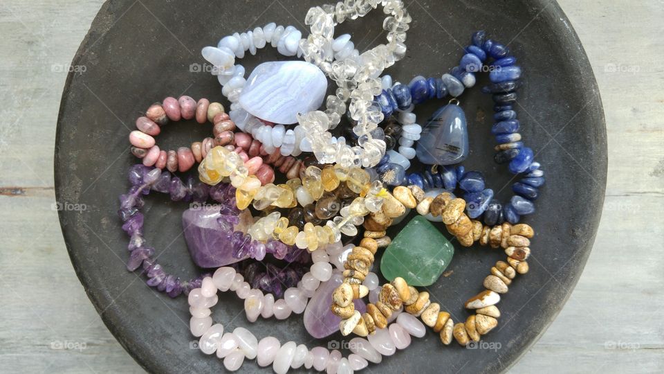 Gemstones in a black bowl on a grey wooden background