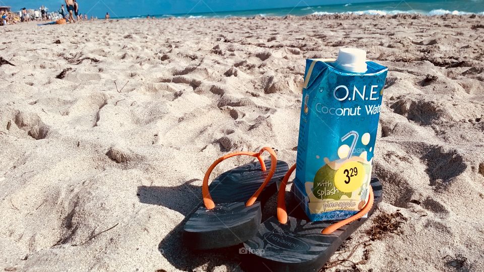 Flip flops on a beach with coconut water