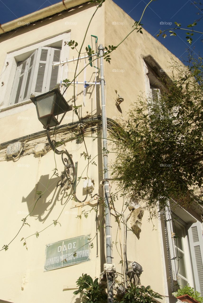 Lantern, jasmine tendrils and street sign on corner of building