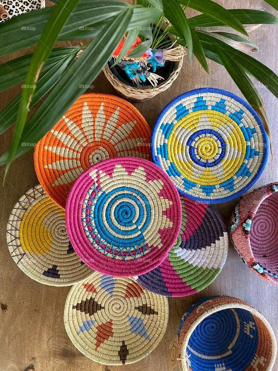 The image shows a group of hand -made dishes of wicker, decorated with colored embroideries with beautiful floral shapes, and is elegantly displayed in a warm corner that combines heritage and beauty, which gives the place an artistic spirit and attr