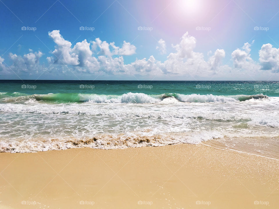 Sea waves rolling on the clean tropical sandy beach at sunny day 