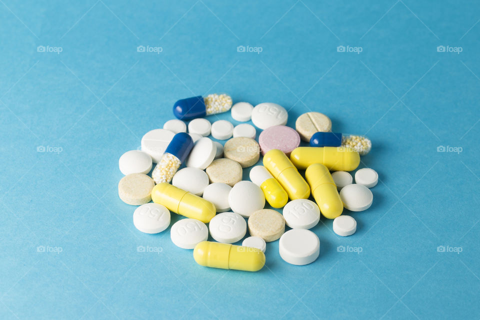 Medicines white,yelow and blue round  shaped pills on blue background