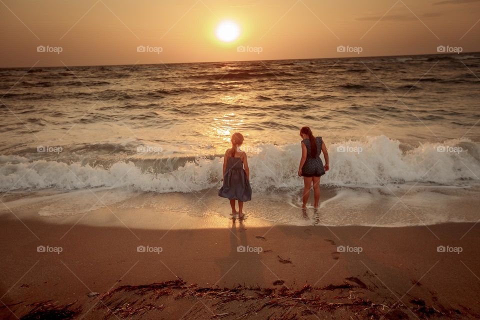 Two sisters on the sea beach at sunset