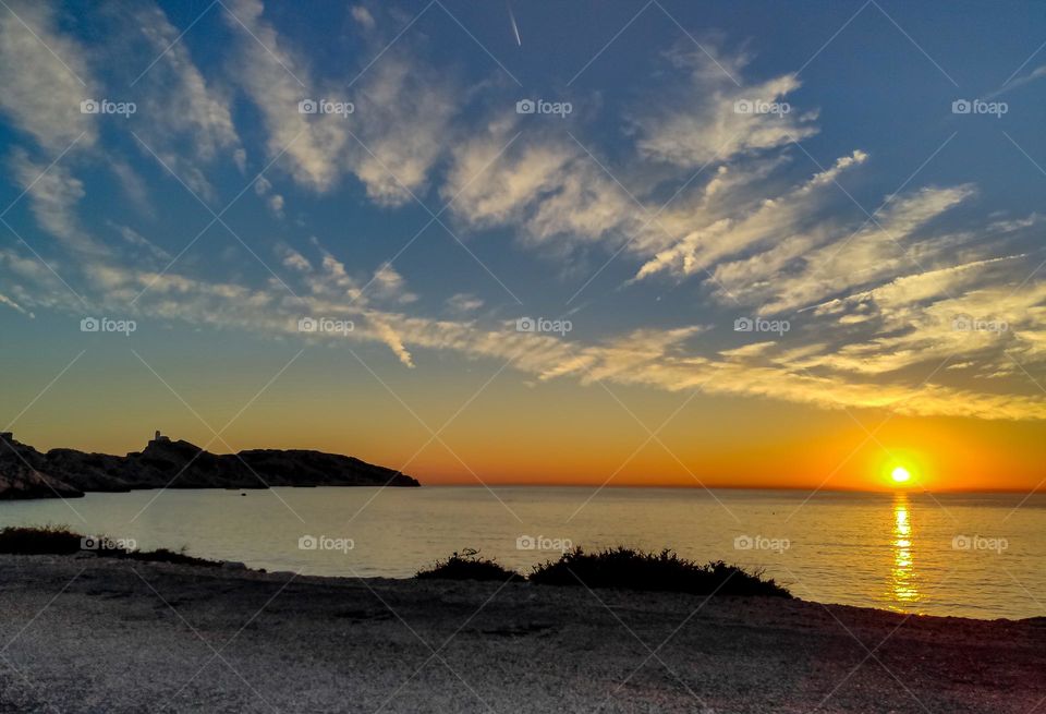 Beautiful view of the white clouds in the evening sunset sky on the Mediterranean Sea with mountains in France on the island of Frioul, close-up side view.