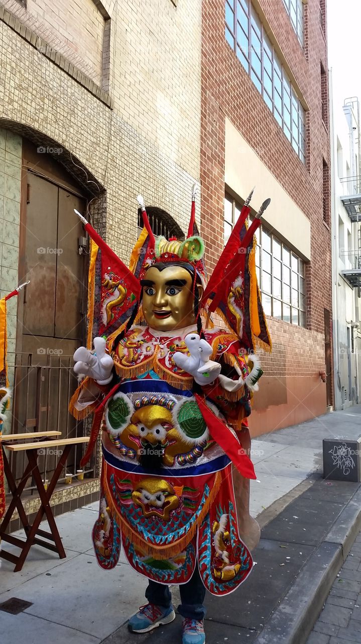 Brightly dressed performer. Performer in golden mask and elaborate costume getting ready to dance