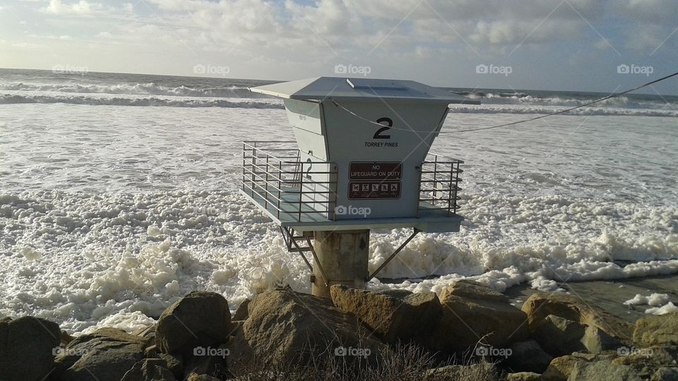 Lifeguard tower at high tide on beach with foamy waves 