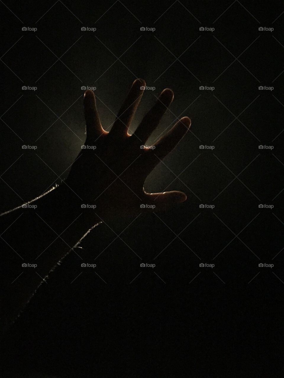 A silhouetted hand blocks out light. 