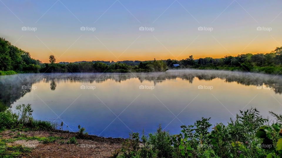 Sunrise over a foggy still Lake