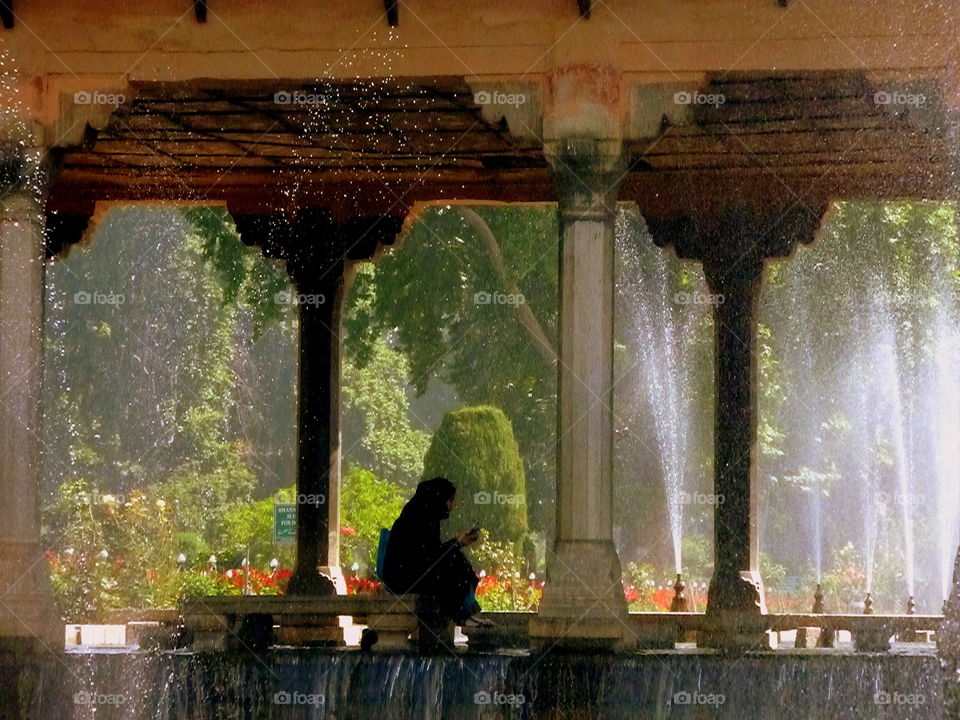 young girl studying among fountains and water