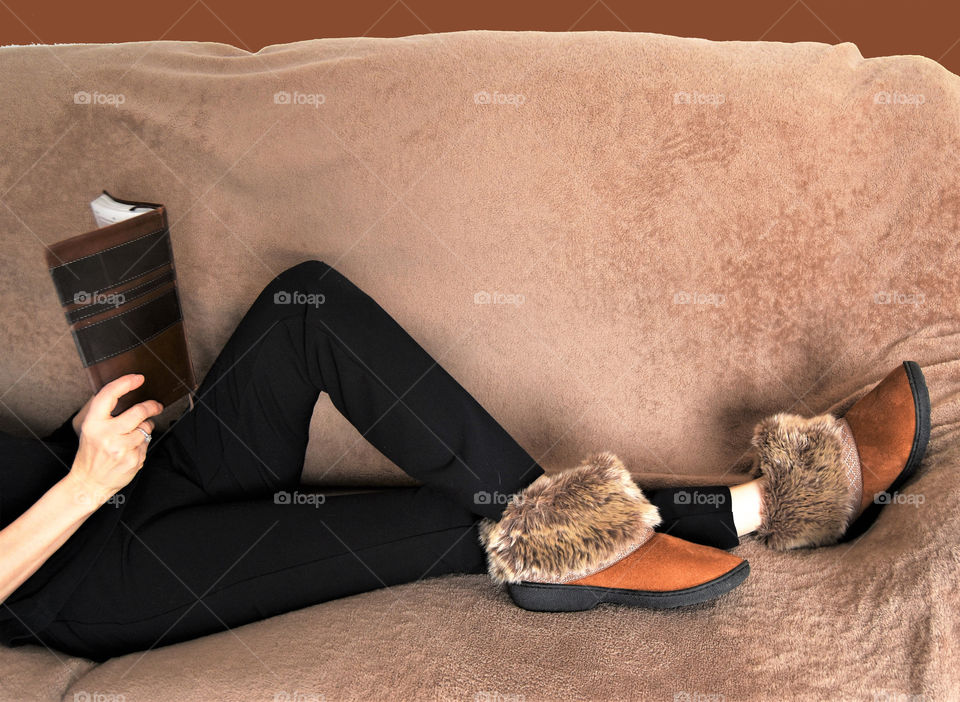 Warm fuzzy slippers worn by a lady while reading a book 