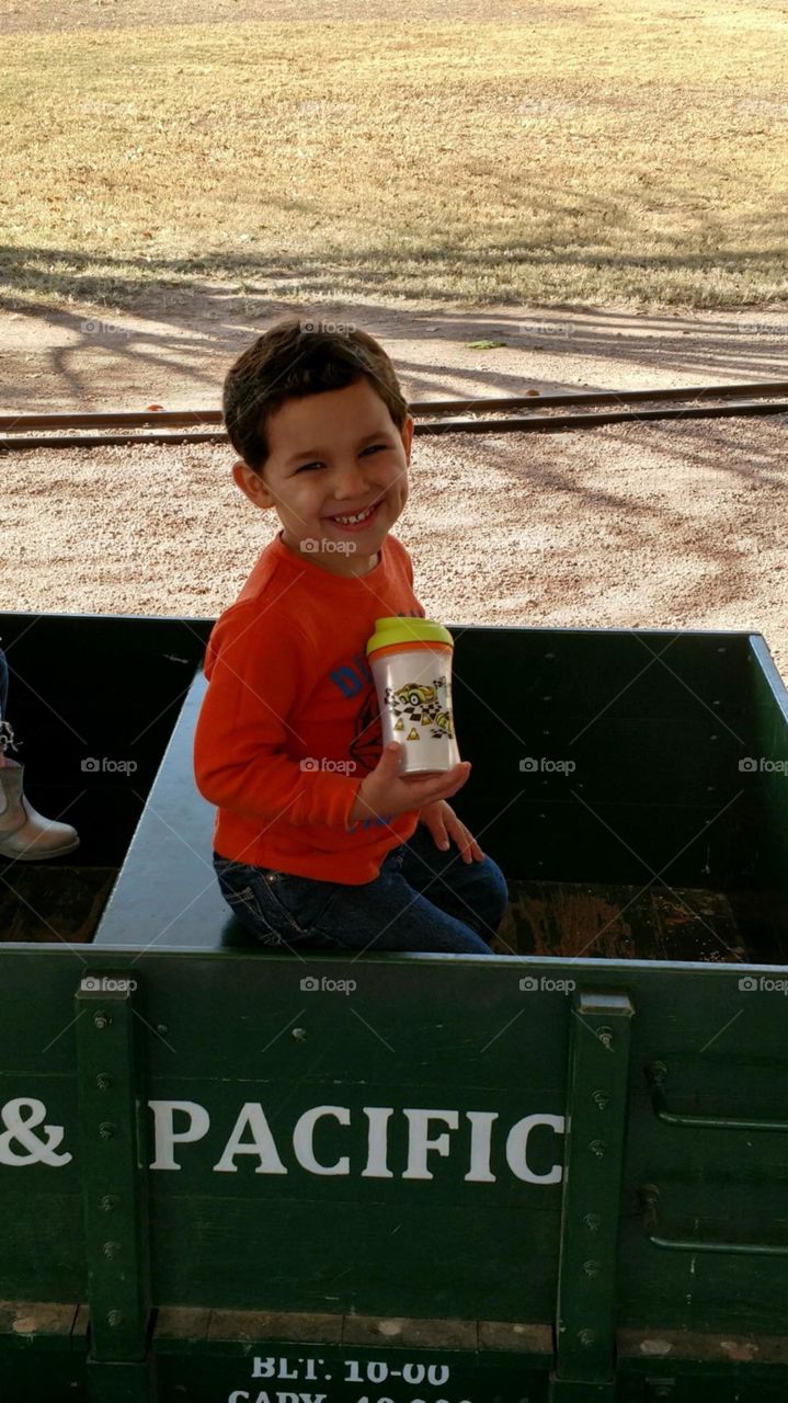 Dimpled boy riding in a toy train.